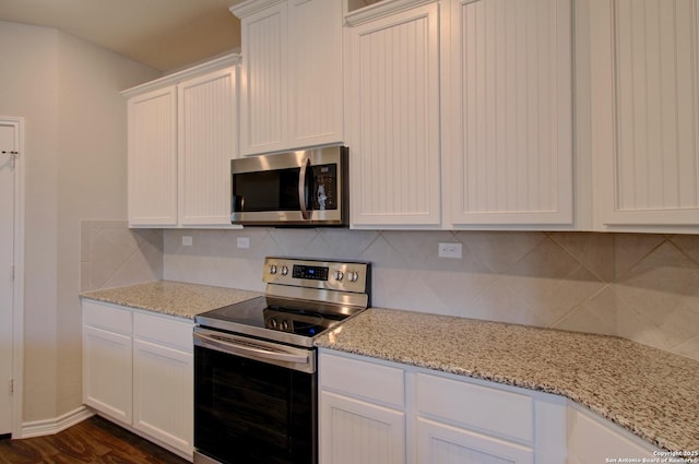 kitchen featuring light stone countertops, dark wood-style flooring, stainless steel appliances, white cabinets, and backsplash