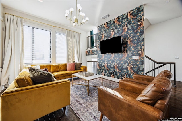 living area with a notable chandelier, visible vents, an accent wall, and wood finished floors