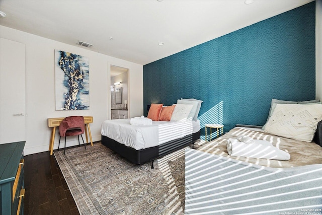 bedroom featuring visible vents, wood finished floors, wallpapered walls, baseboards, and an accent wall