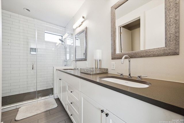 bathroom featuring a sink, double vanity, wood finished floors, and a shower stall