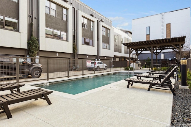 community pool with a patio area, area for grilling, and fence