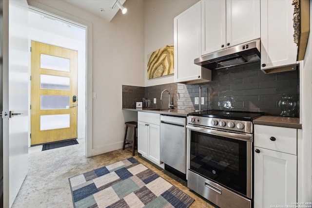 kitchen with tasteful backsplash, under cabinet range hood, stainless steel appliances, white cabinetry, and a sink