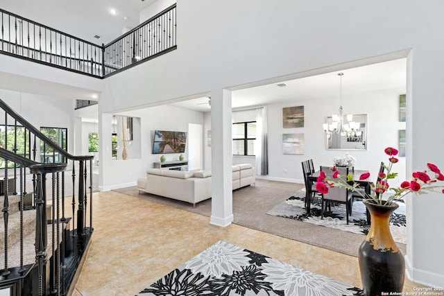 interior space with tile patterned floors, stairway, an inviting chandelier, baseboards, and a towering ceiling