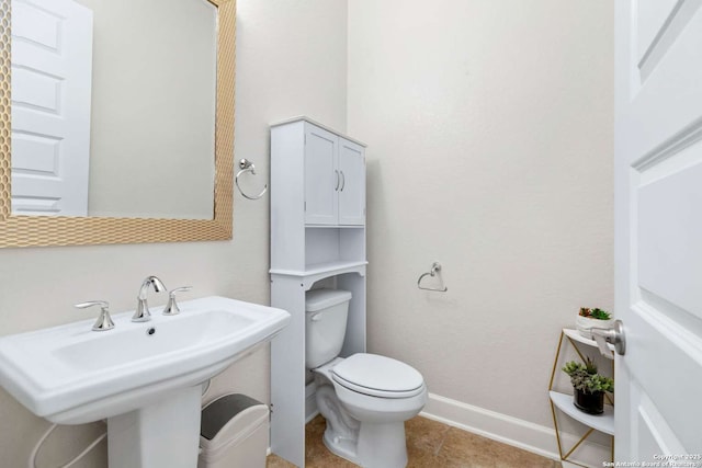 half bathroom with tile patterned floors, toilet, baseboards, and a sink