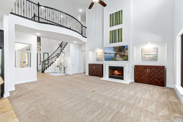 unfurnished living room with stairway, carpet, baseboards, and a warm lit fireplace