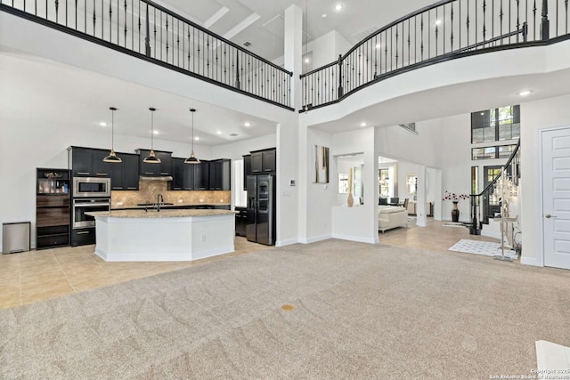 kitchen with dark cabinetry, a sink, appliances with stainless steel finishes, light carpet, and open floor plan