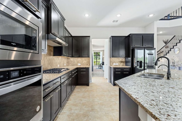 kitchen featuring visible vents, appliances with stainless steel finishes, light stone countertops, and a sink