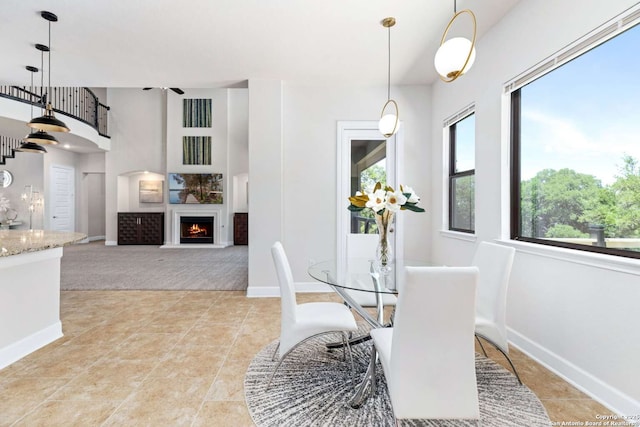 dining room featuring light tile patterned floors, baseboards, and a lit fireplace