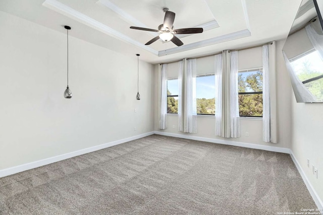 carpeted spare room featuring ceiling fan, a tray ceiling, baseboards, and ornamental molding