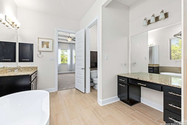 full bath featuring a freestanding tub, baseboards, toilet, and two vanities