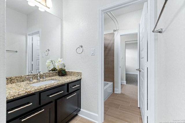 bathroom featuring vanity, shower / bath combination, baseboards, and wood finish floors