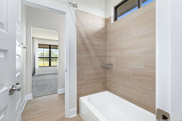 bathroom with bathing tub / shower combination and baseboards