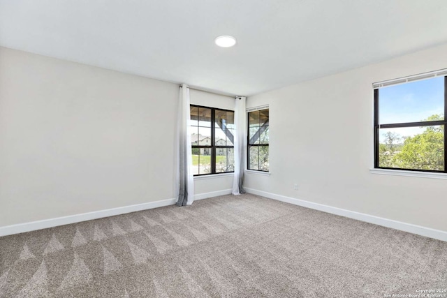 unfurnished room featuring baseboards, carpet, and plenty of natural light