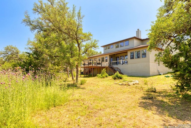 rear view of property featuring stairway, a deck, and a chimney