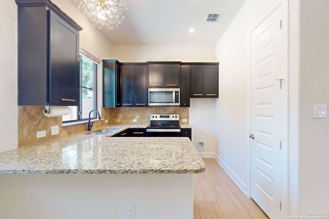 kitchen with a sink, light stone countertops, tasteful backsplash, and appliances with stainless steel finishes