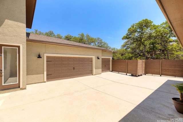 garage featuring driveway and fence