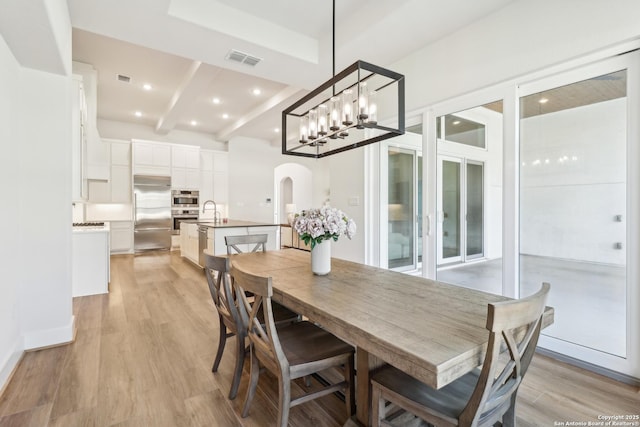 dining room featuring arched walkways, visible vents, beam ceiling, and light wood-style floors