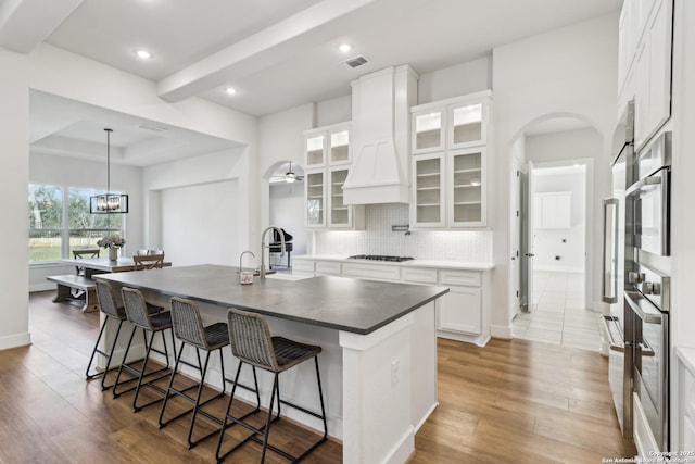 kitchen with oven, a sink, tasteful backsplash, a breakfast bar area, and white cabinets