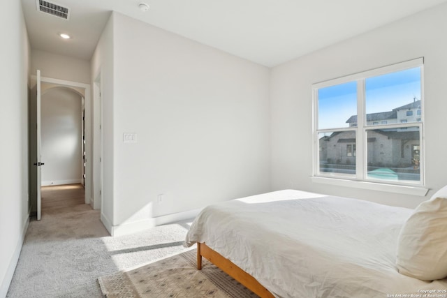 bedroom featuring visible vents, light carpet, and baseboards