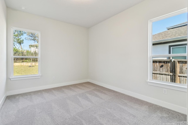 carpeted empty room featuring baseboards