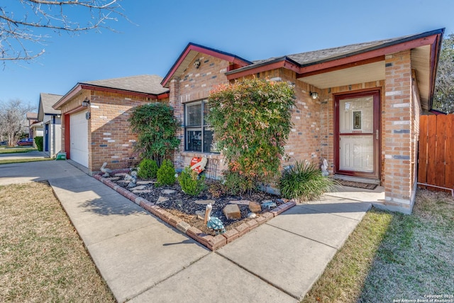 view of front of home featuring brick siding, an attached garage, concrete driveway, and fence