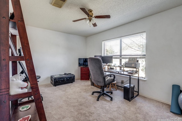 office space featuring a ceiling fan, baseboards, carpet, visible vents, and a textured ceiling