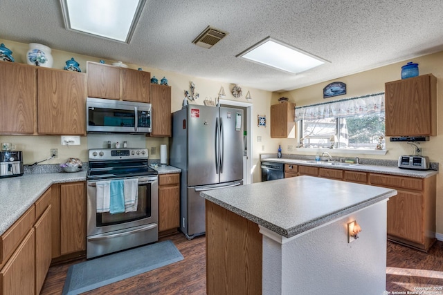 kitchen with visible vents, appliances with stainless steel finishes, dark wood-style floors, a textured ceiling, and a sink