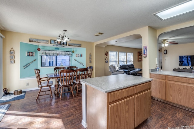 kitchen featuring a kitchen island, dark wood-type flooring, open floor plan, light countertops, and arched walkways