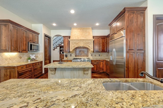 133 Fair Spgs, Boerne, TX 78006 - kitchen featuring appliances with stainless steel finishes, a sink, light stone countertops, a textured ceiling, and recessed lighting