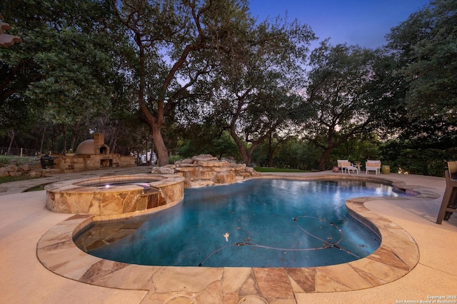 133 Fair Spgs, Boerne, TX 78006 - pool at dusk featuring a patio, view of scattered trees, and a pool with connected hot tub