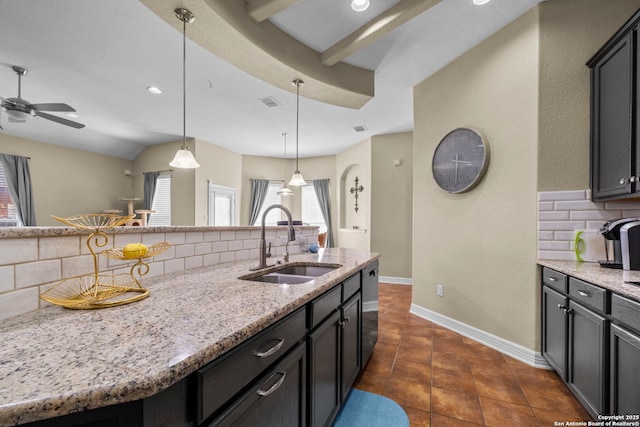 kitchen with light stone counters, baseboards, a sink, decorative backsplash, and hanging light fixtures