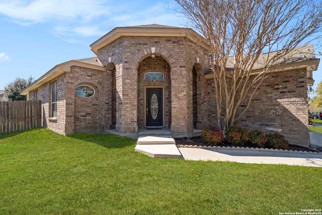 view of front of house with brick siding, a front lawn, and fence