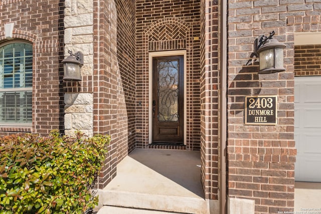 property entrance featuring a garage and brick siding