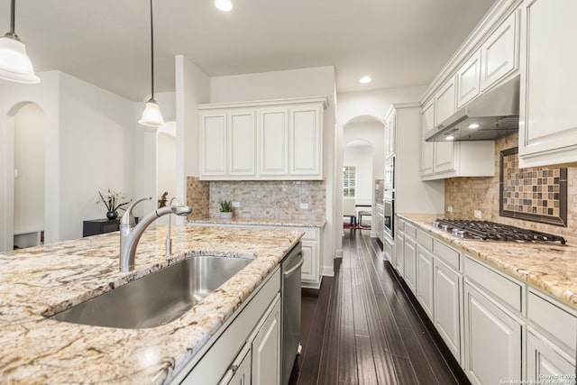 kitchen featuring dark wood-style floors, arched walkways, a sink, appliances with stainless steel finishes, and under cabinet range hood