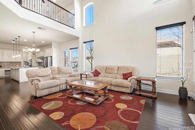 living room featuring a chandelier, baseboards, visible vents, and dark wood finished floors