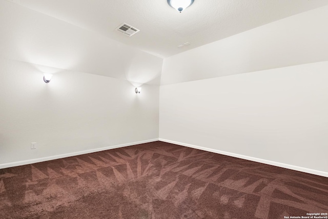 carpeted spare room featuring visible vents, lofted ceiling, and baseboards