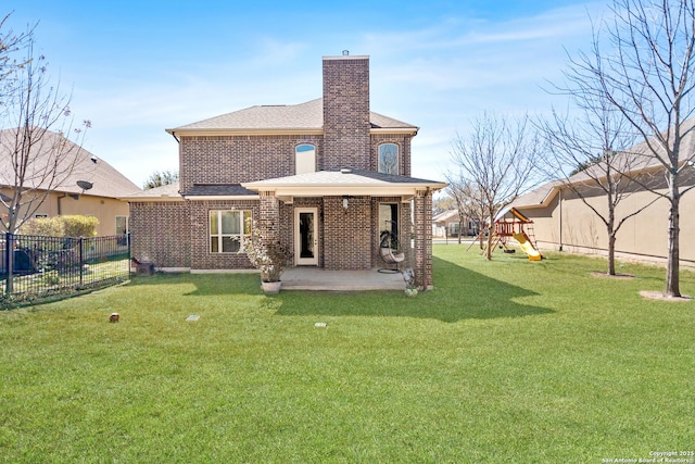 rear view of house with a lawn, a fenced backyard, a playground, a chimney, and a patio area