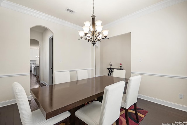 dining room featuring visible vents, baseboards, ornamental molding, dark wood-style floors, and a notable chandelier