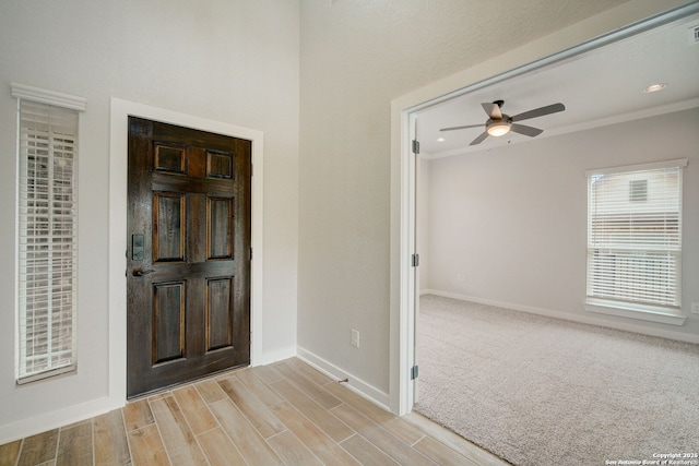 foyer entrance featuring ceiling fan, baseboards, light wood-type flooring, and ornamental molding