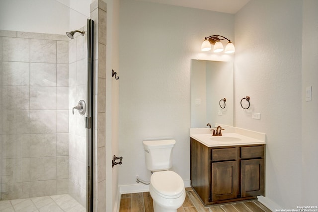 full bathroom with wood finish floors, toilet, a shower stall, baseboards, and vanity