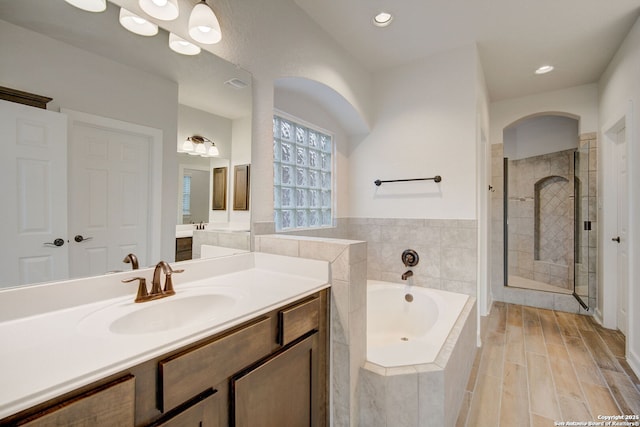 full bathroom with a shower stall, wood finish floors, recessed lighting, a bath, and vanity