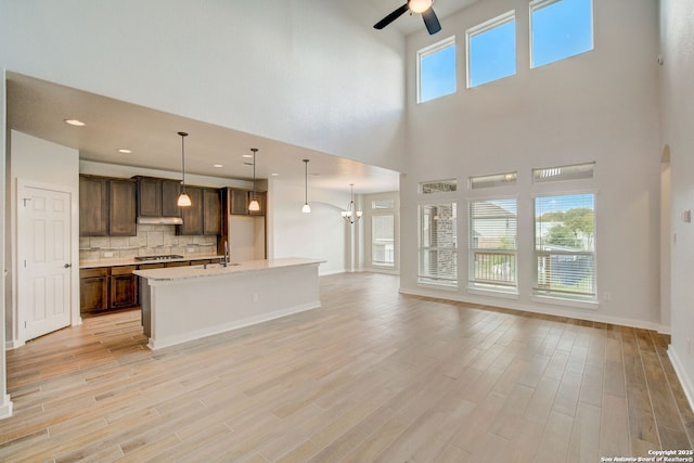 kitchen featuring light wood finished floors, open floor plan, decorative backsplash, and dark brown cabinetry