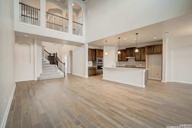 kitchen featuring built in microwave, light countertops, open floor plan, light wood-style floors, and tasteful backsplash