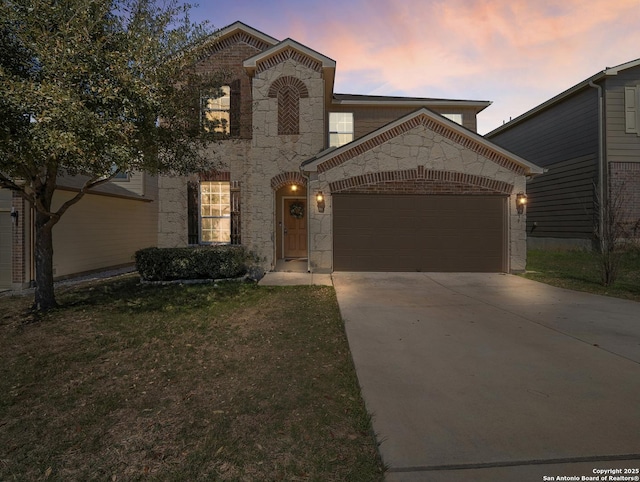 view of front of home featuring concrete driveway, an attached garage, a lawn, and brick siding