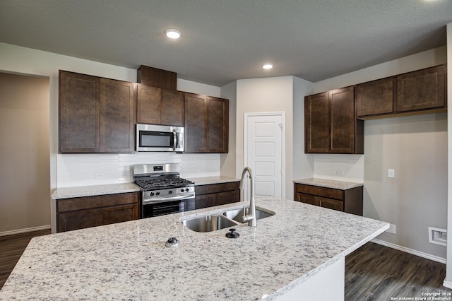 kitchen featuring dark brown cabinetry, dark wood-style flooring, appliances with stainless steel finishes, and a sink