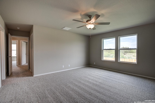 empty room featuring a ceiling fan, carpet, visible vents, baseboards, and a textured ceiling