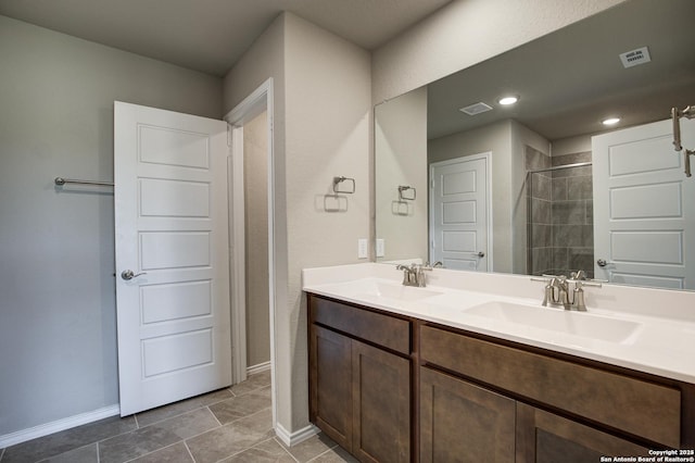 full bath with double vanity, visible vents, a tile shower, and a sink