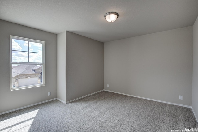 spare room with carpet flooring, baseboards, and a textured ceiling