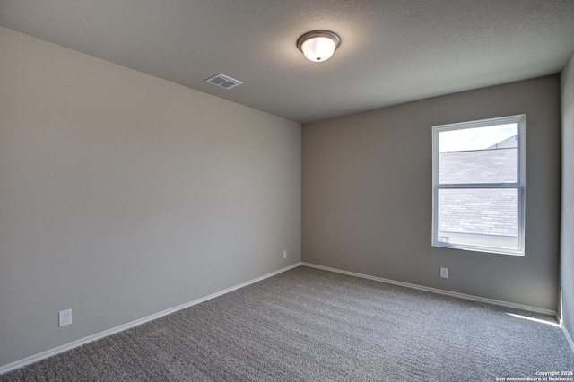 empty room with carpet flooring, baseboards, visible vents, and a textured ceiling