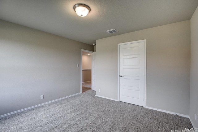 unfurnished bedroom featuring visible vents, carpet flooring, a textured ceiling, and baseboards